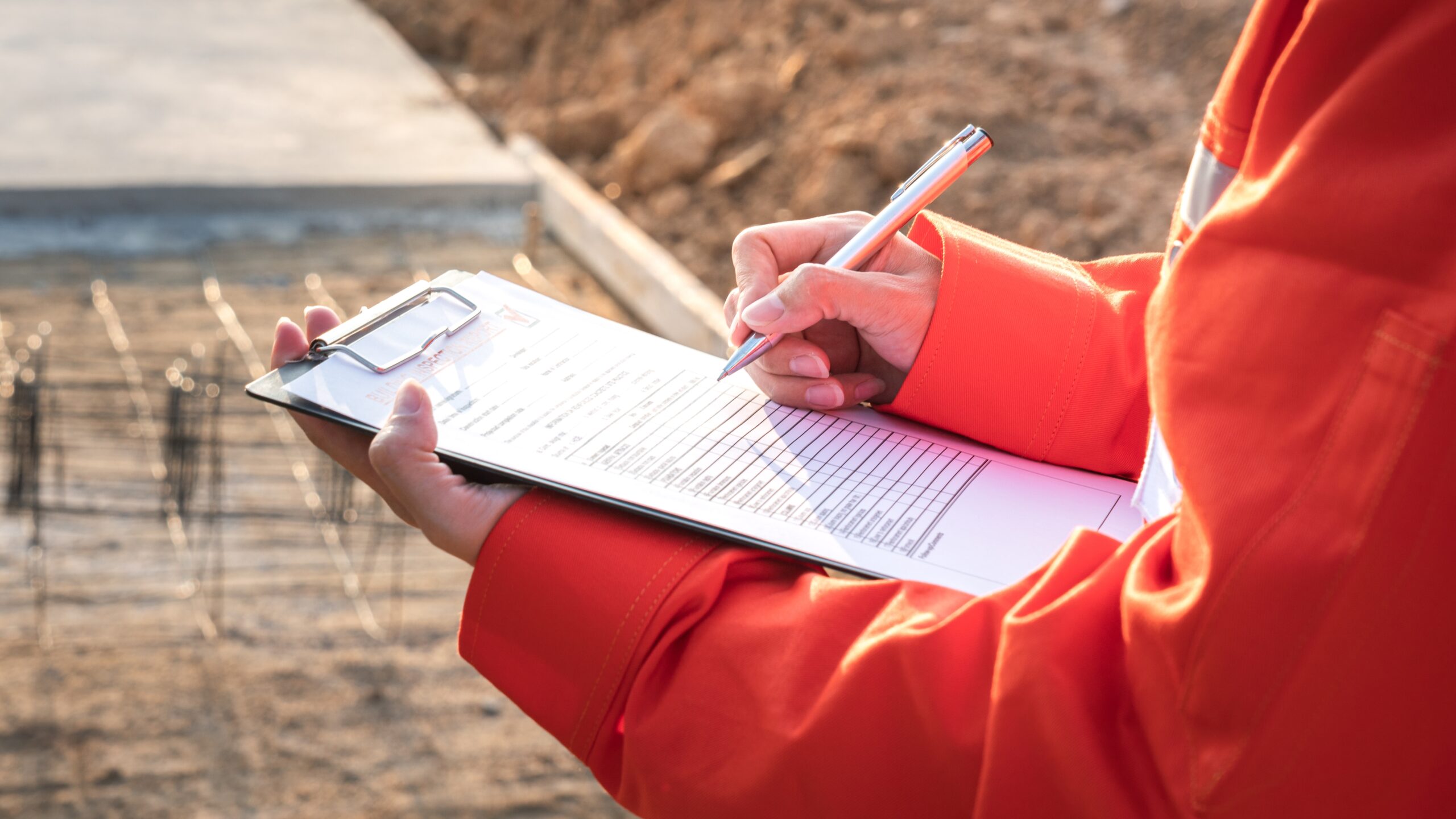 A worker performing Asbestos Site Audits while checking off items from a checklist in the sun