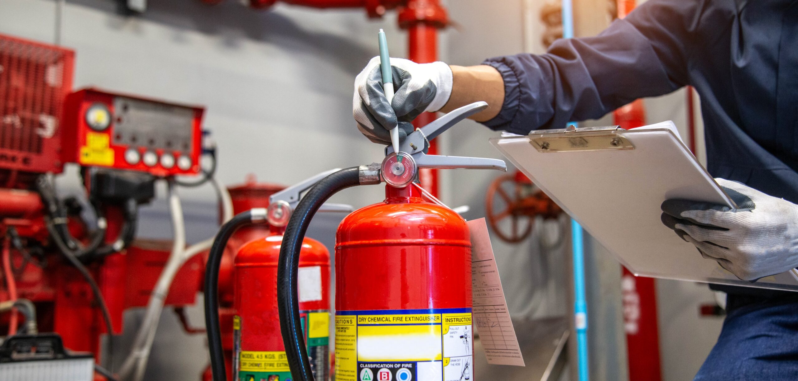 A inspection worker inspecting a fire extinguisher while holding a checklist on a clipboard
